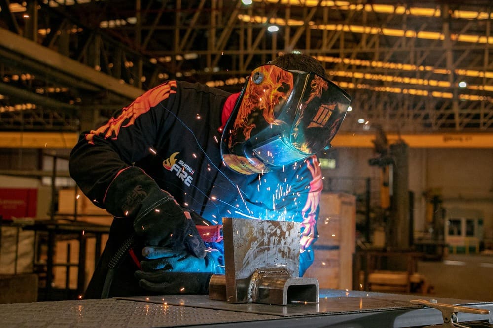 Soldador trabalhando em junta de metal em indústria